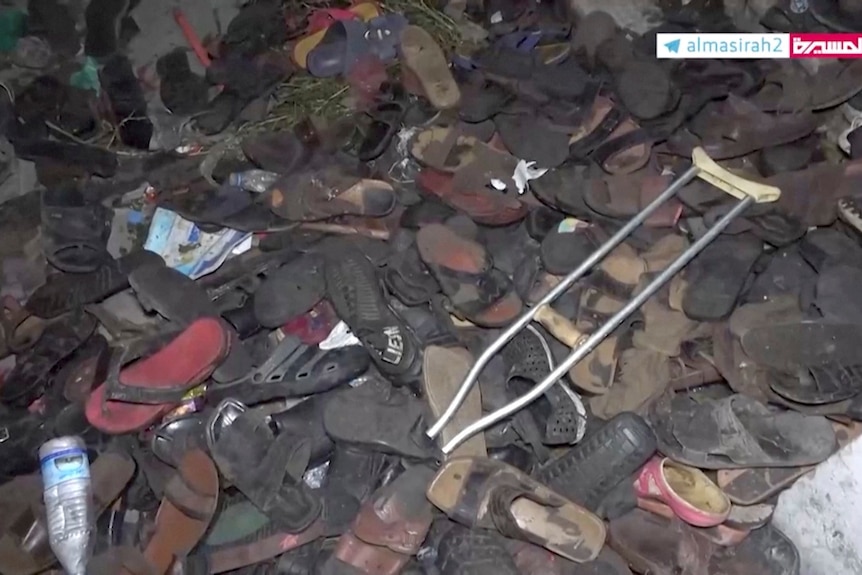 A large and messy pile of footwear of various sorts and a crutch is left in a heap after a stampede.