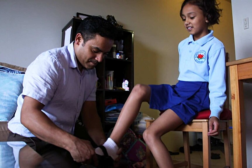 Cleaner Tirtha Raj Karki helps his daughter put her shoes on.
