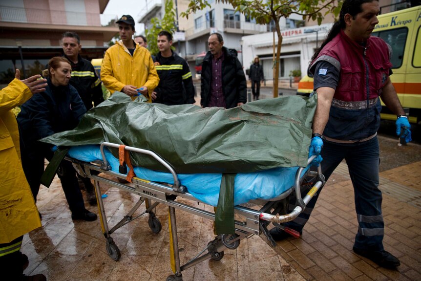 Medics carry the body of an elderly woman in the municipality of Mandra western Athens.
