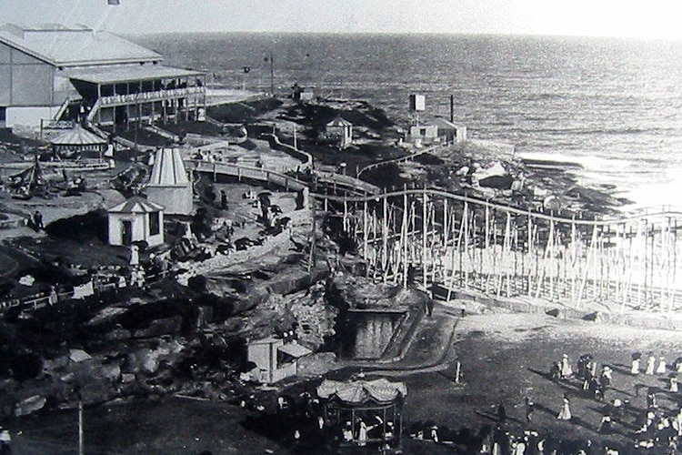 A theme park with a roller coaster at a beach.