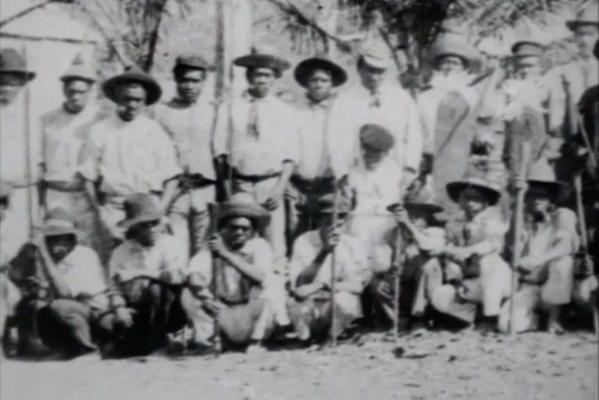 A black and white photo of a group of Pacific Islander men holding tools for cutting sugar cane fields