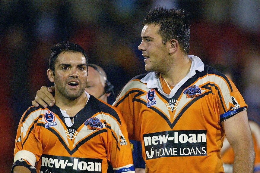 Two men celebrae after winning a rugby league match. 