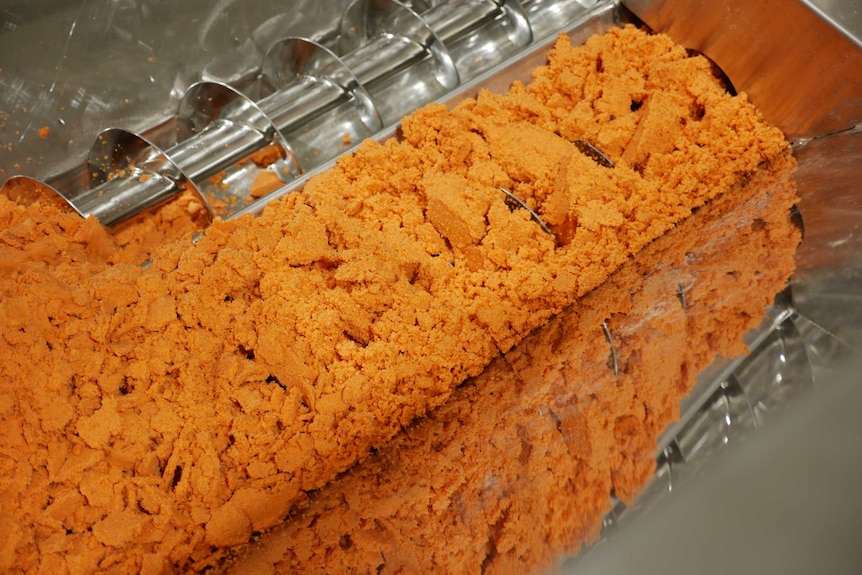 An orange coloured flour going through a mechanical process.