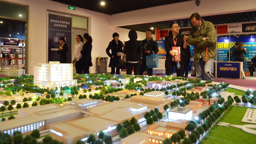 People walk past a display model of Hanya Federal's Melbourne development