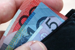 A hand reaches for money in a wallet (ABC News: Giulio Saggin)