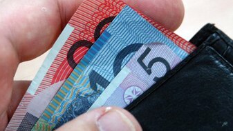 A hand reaches for money in a wallet (ABC)