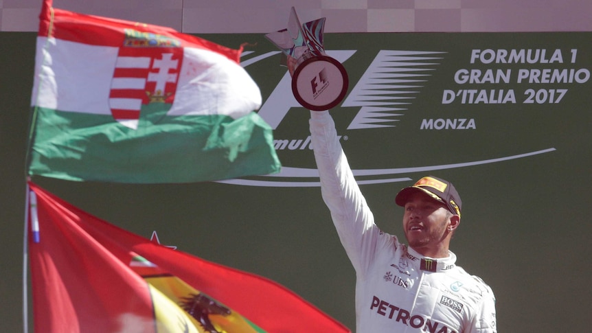 Lewis Hamilton raises trophy celebrating