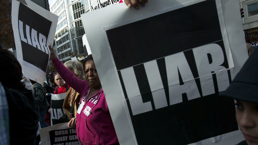 Protesters carrying signs that say "LIAR" in protest against the US administration's policy on AIDS