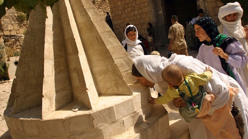 A Yazidi sect devotee kisses a monument in the yard of the main Lalish temple at the town of Sheikh Hadi.