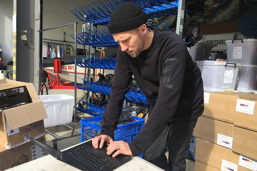 Man checks stock on computer at Melbourne Snowboard Centre