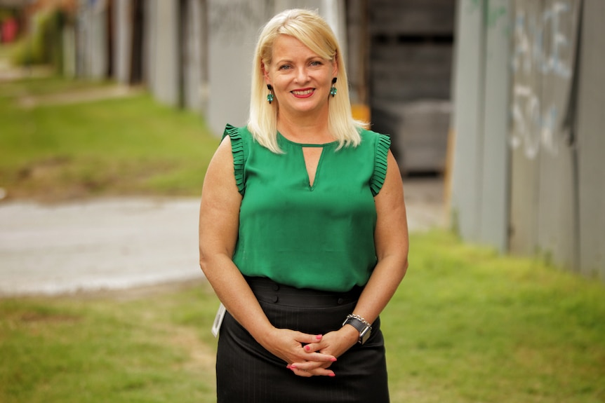 Krista Adams stands outside and smiles, looking at the camera.