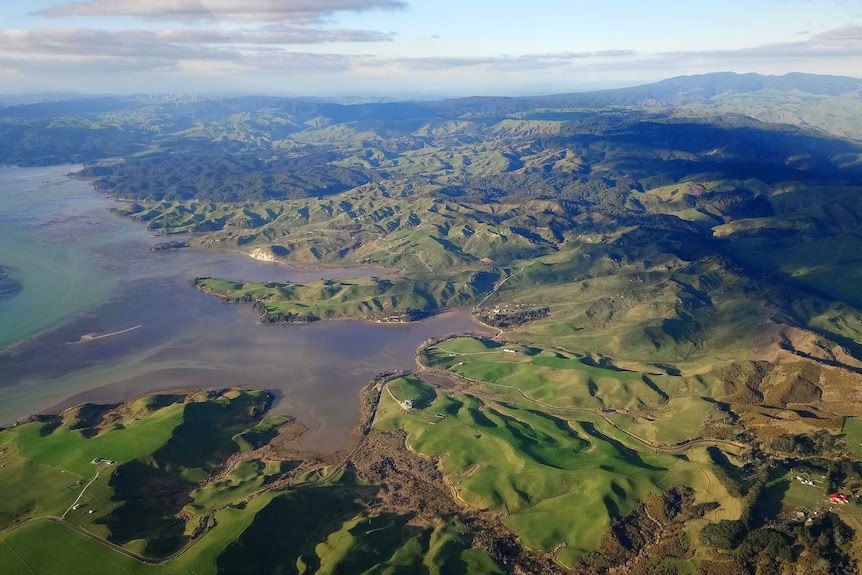 An aerial image of a lake and green hills.