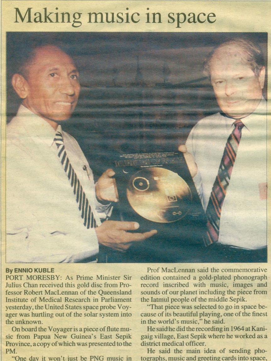 A slightly yellowed photo of a newspaper story. The photo is of a man handing a golden record to another man.