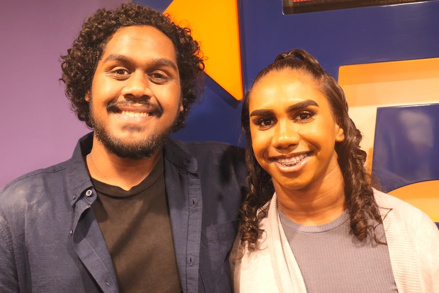 Two young First Nations actor smile at camera inside a movie theatre