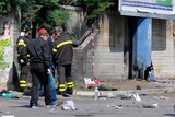 Italian policemen and firefighters inspect the site where a bomb exploded in front of a school.