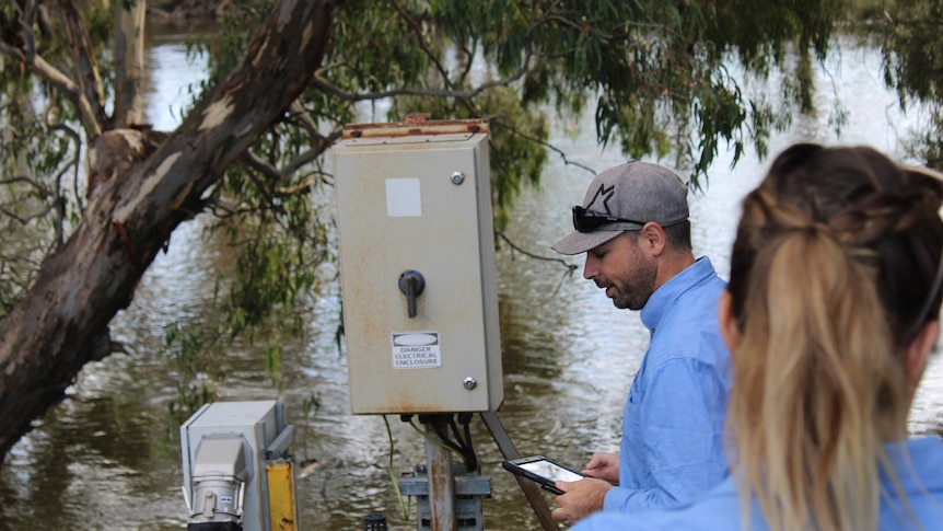 A man with a tablet inspects an irrigation pump