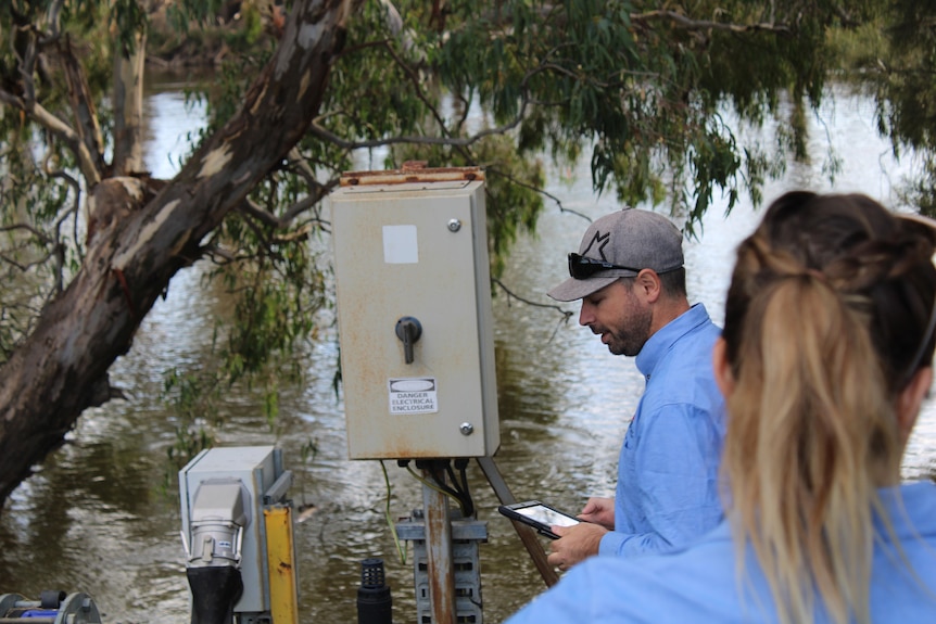 A man with a tablet inspects an irrigation pump