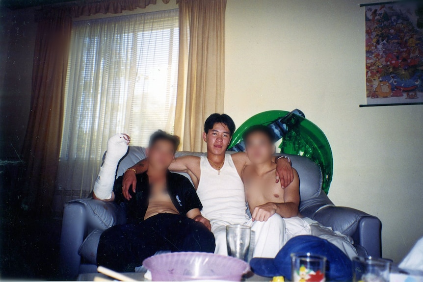 Three teenage boys sitting in couch, one with cast on arm.