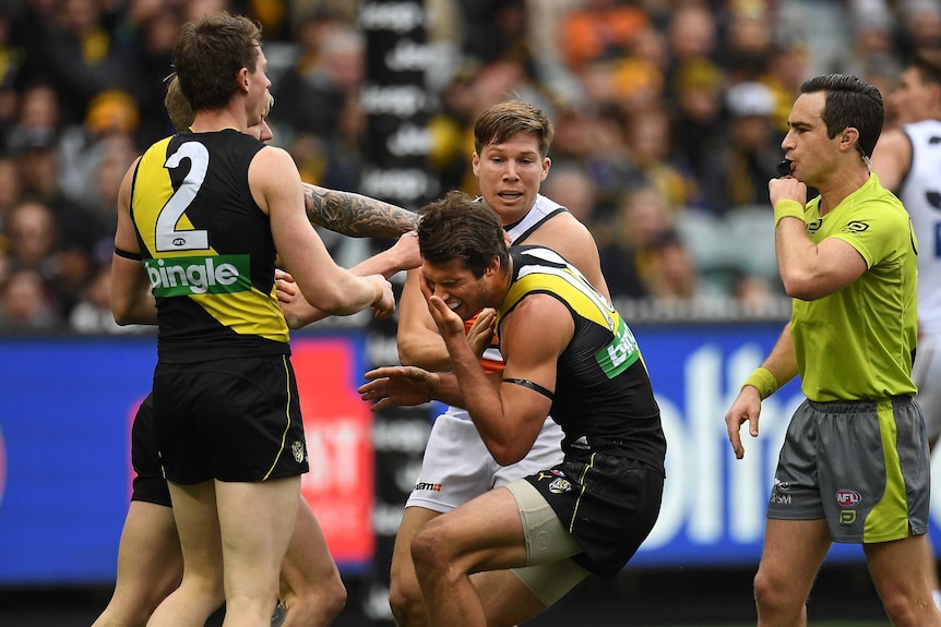 Alex Rance grabs his face after Toby Greene hit it.