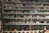 Old fading and dusty beer cans and bottles on shelves behind the bar at the Grove Hill hotel