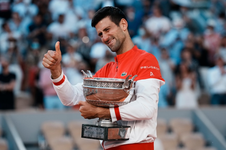 Novak Djokovic holds his thumbs up with the French Open trophy