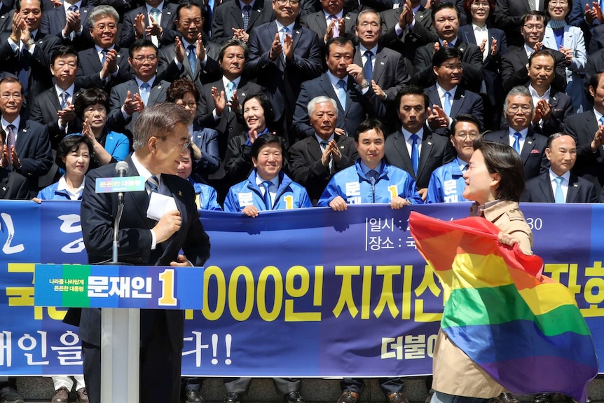 A protester holding a rainbow flag, approaches South Korea's presidential candidate Moon Jae-in at National Assembly in Seoul.