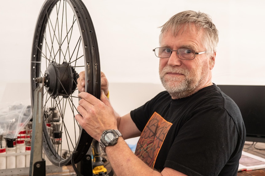 Henry Shiel repairs an e-bike wheel
