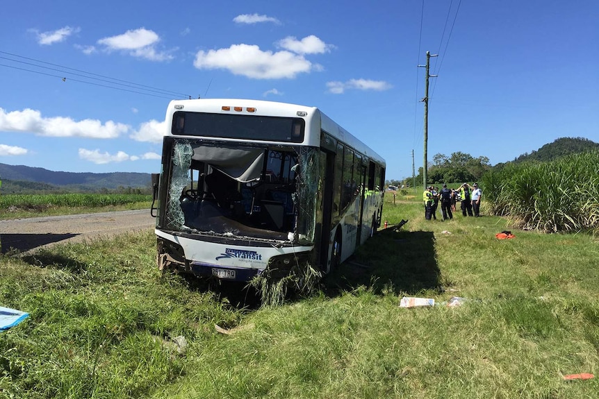 Wreck of bus beside a road with police in the background