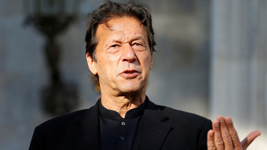 A close up of Imran Khan in a black suit as he talks and gestures with his hand.