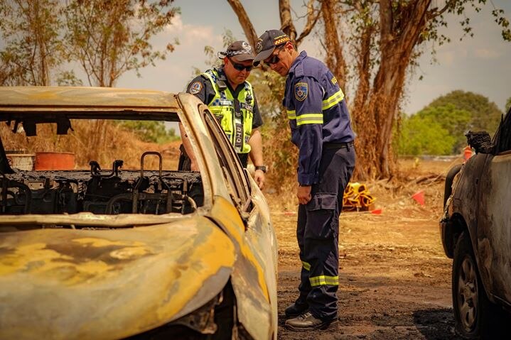 Emergency services examine a burnt our car in Berrimah.