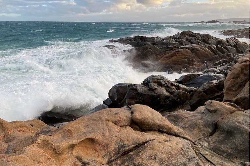 Large waves crashing over rocks in the ocean.