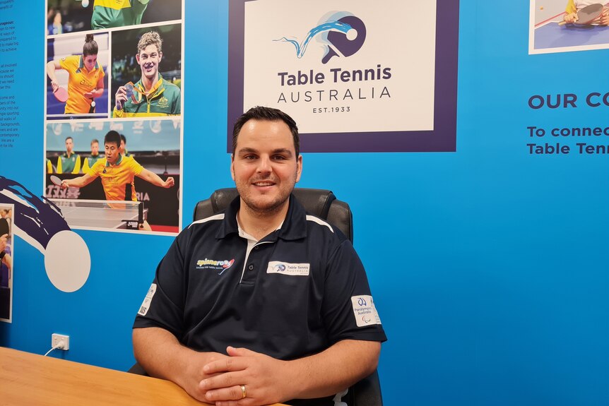 Man at desk with table tennis australia sign