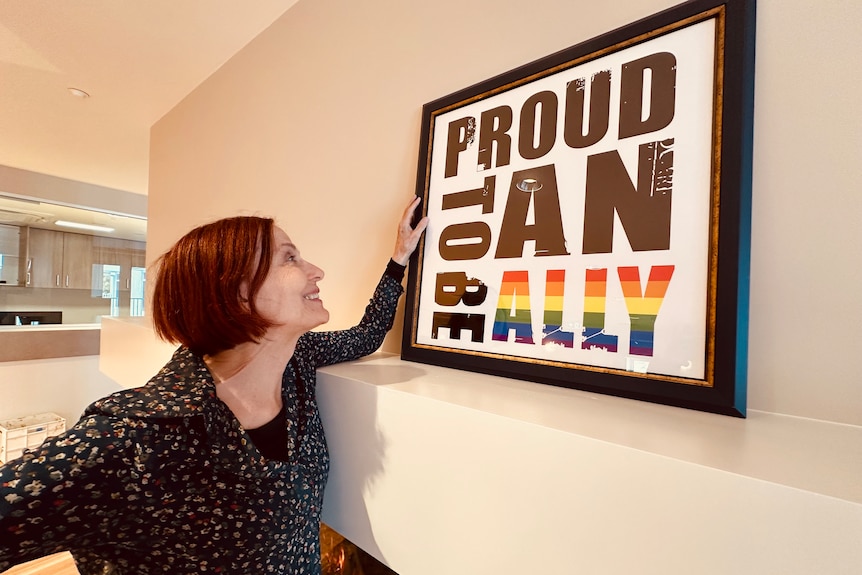 Woman smiles at a poster that says Proud to be an Ally  
