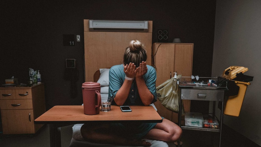 Sarah Jade in hospital with her head in her hands on a hospital bed.