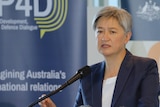 Penny Wong standing at a podium. 
