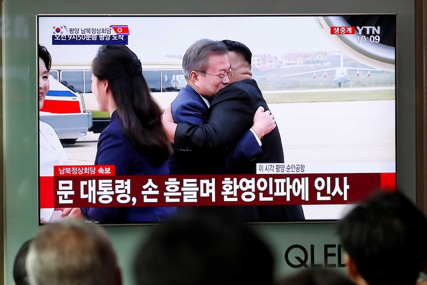 People watch a televised broadcast in Seoul as Moon Jae-in and Kim Jong-un hug as they meet in Pyongyang.