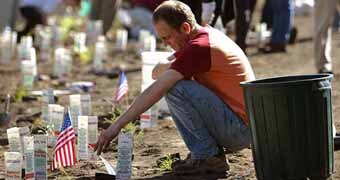 Man kneels in front of flags in September 11 memorial.