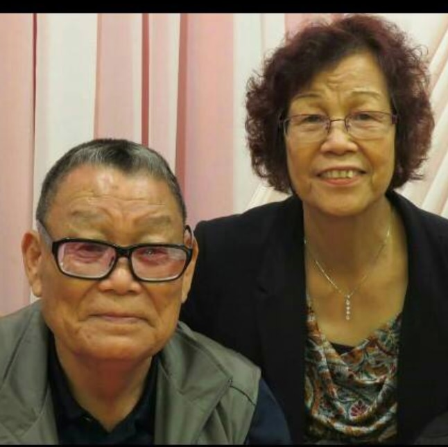 An elderly Hong Kong man and his wife sits next to each other