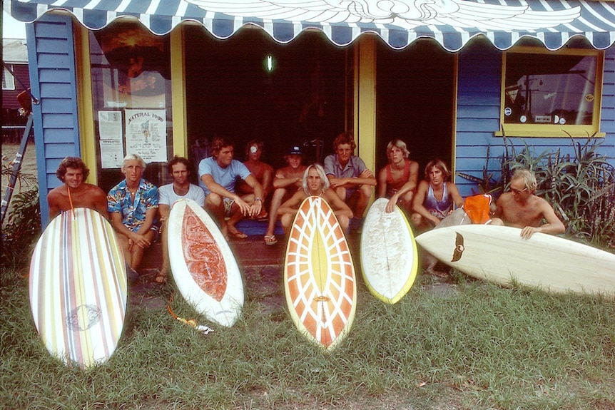 A group of surfers with their boards outside a Gold Coast shop in the 1970s