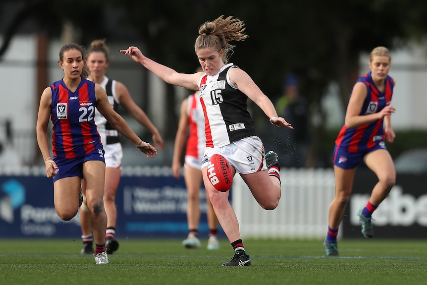 Tara Bohanna kicks the ball wearing a red white and black striped top