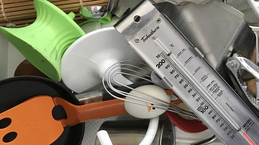 Kitchen utensils strewn in a drawer including spatula, thermometer, rolling pin, dough hook