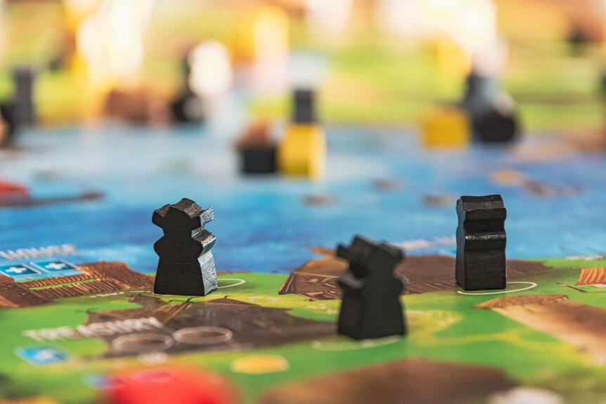 A generic image of an unnamed board game, with small wooden pieces in focus.