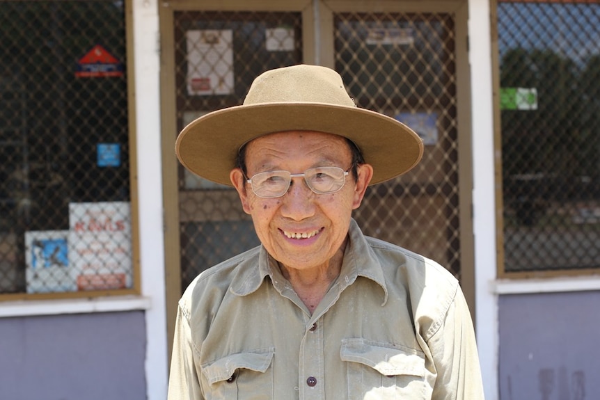 An elderly man stands in front of his now-closed general store.