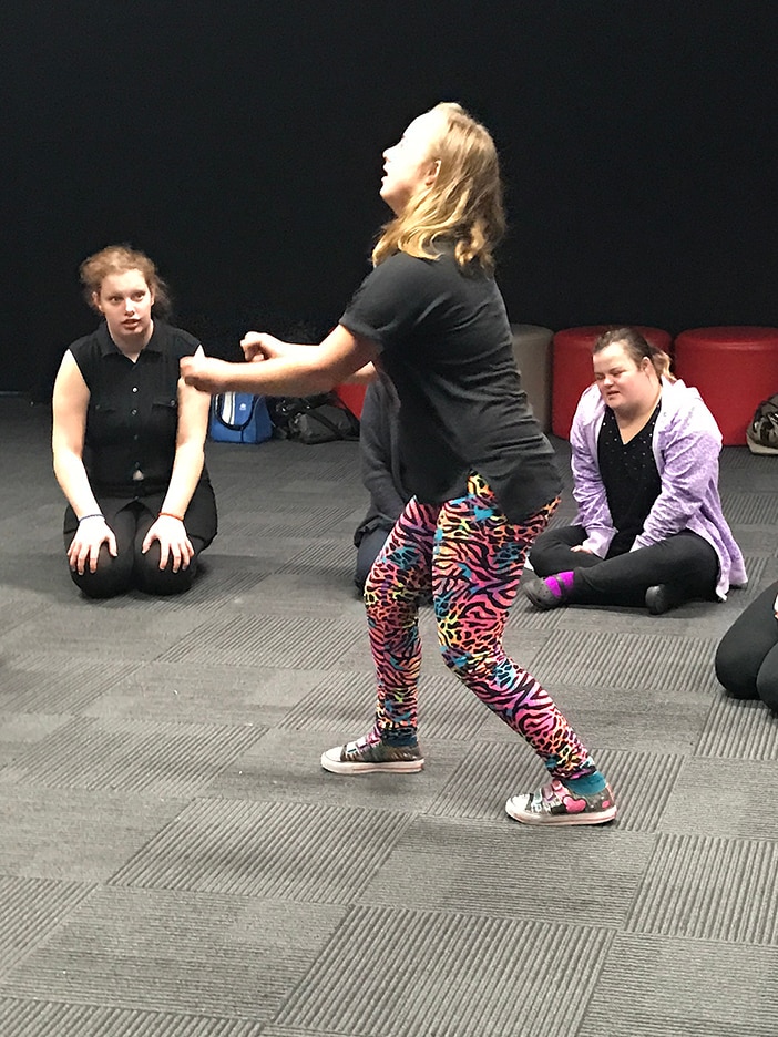 Girl doing interpretive dance watched by two others.