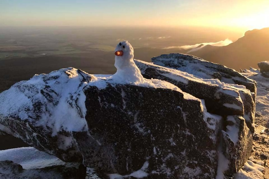 A carrot-nosed snowman at Bluff Knoll in WA's Great Southern with the sun behind it.