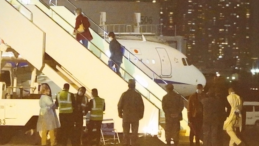 Passengers board a Qantas plane on a runway