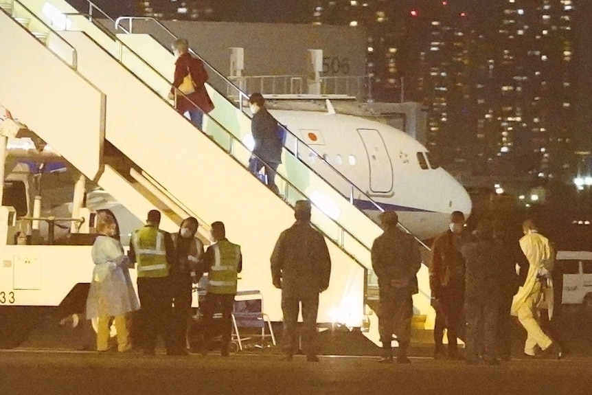 Passengers board a Qantas plane on a runway