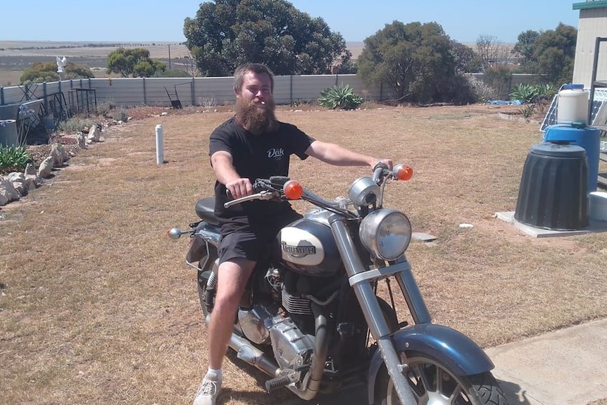 Man with beard on motorcycle in rural setting