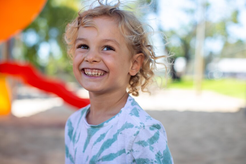Smiling four year old boy with blonde hair and white teeth