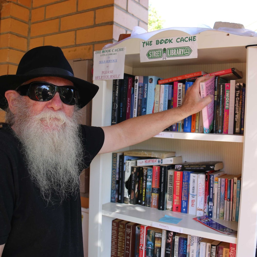 A man takes a book from a street library.